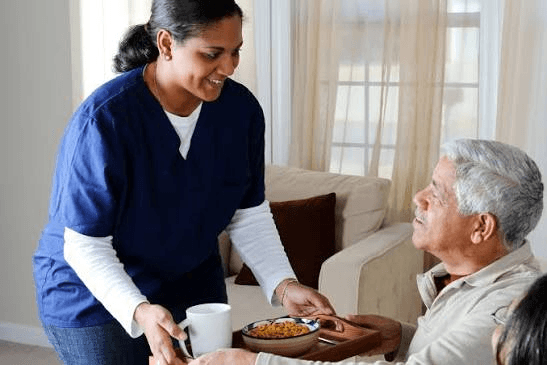 A Careway care coordinator serving a meal to an elderly man at home